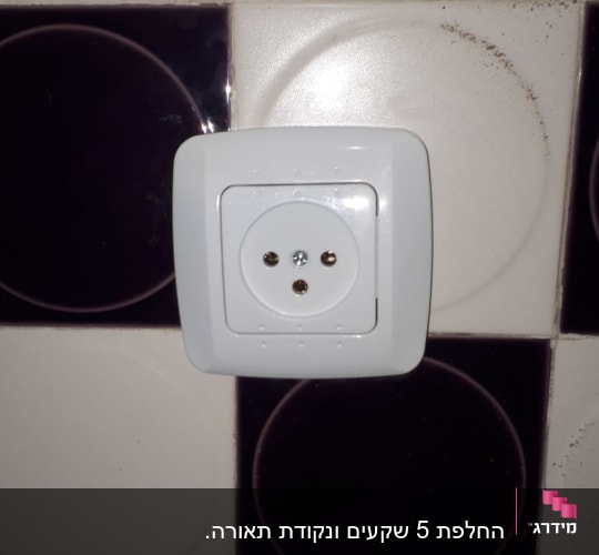 שקע חשמלי לבן על קיר מרוצף